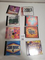 Eight dance music CDs displayed on a flat surface showing various compilation titles and colorful cover art.