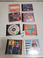 Eight dance music CDs arranged on a white surface in two rows of four.