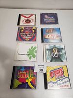 Eight dance music CDs arranged in two rows on a white surface. Covers feature various logos, titles, and artwork related to electronic and dance music compilations from around 2000.