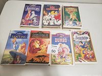 Seven Disney animated animal movies on VHS in good condition, including The Aristocats, 101 Dalmatians, Bambi, The Lion King, The Lion King II, Dumbo, and Snow White and the Seven Dwarfs.