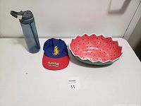Lot with a translucent blue Contigo water bottle, blue and red Pokemon Pikachu hat, and watermelon themed ceramic dish