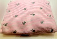 Folded pink and white striped sheet with scattered green palm tree prints showing fabric pattern and texture.