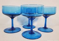 Four Empoli aqua blue crystal coupe dessert cups arranged together showing size and shape.