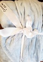 Rolled and tied powder blue blanket showing approximate size measurement tag indicating queen size 142x.
