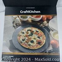 Product packaging showing the pizza stone with a cooked pizza on top, garlic, herbs, and other ingredients in the background.