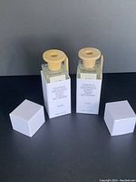 Two Omnibus SUN Linen Fragrance Diffuser bottles with caps removed showing wooden stoppers, front view.