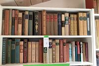 Three shelves filled with classic hardcover books, various titles visible including 'Nostromo,' 'The Swiss Family Robinson,' and others.