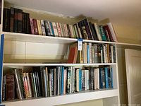 Wide shot showing two shelves filled with numerous books on nautical and boating topics plus some related subjects.