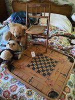 Photo showing the toddler-sized wooden chair, two teddy bears, and the carrom board placed on a patterned bedspread.