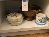 Shelf with Hall covered casserole, copper colander, ceramic bowl, plastic pitcher