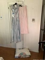 Two vintage dresses hanging on closet doors with quilt and blanket folded below