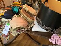 Photo showing several vintage hats in a hat box and on table including a black hat box, beige and blue hats