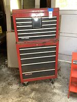 Front view of stacked red and black Craftsman metal tool chests showing wear and rust, placed on concrete floor.