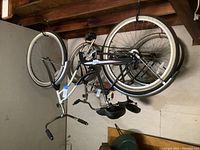Photo showing the full bike hanging, revealing silver frame, black seat, and 26 inch wheels.