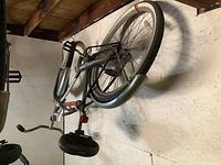 Side view of Outfitters cruiser bike hanging on a wall, showing frame, saddle, handlebars, wheels, and pedals.