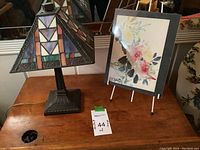 Overview showing stained glass lamp and floral artwork on table