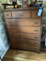 Full view of wooden dresser with six drawers, showing metal handles and overall condition