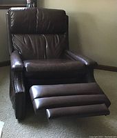 Front view of Barco dark brown leather recliner with extended footrest showing leather cushion and studded armrests.