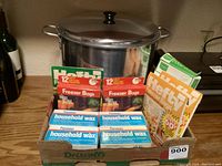 Large stainless steel canning pot with lid, Hefty freezer bags and Parowax household wax boxes in a cardboard box.