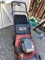 Full view of the red Snapper lawn mower showing handle, deck, and wheels on outdoor concrete surface.