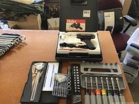 Overall lot view showing Weller soldering iron kit in black case beside multiple socket wrenches and tools on table.