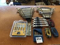 Overview photo of all the tools including wrench sets, drill bits, and hex key sets arranged on a wooden table