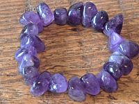 Close-up image showing the amethyst chip bracelet formed in a circle on a wooden surface