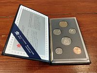Black protective folder opened showing 7 coins in foam slots and certificate from Royal Canadian Mint.
