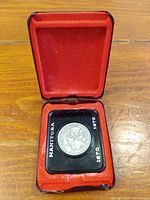 Photo of the 1970 Canadian Manitoba Centennial dollar coin in its red velvet-lined presentation case showing the coin and case condition.