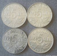 Four 1932 Canadian five cent coins reverse side showing denomination, maple leaves, and date.