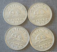 Photo showing the reverse side of four Canadian 1940 nickels featuring the beaver design and denomination.