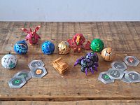 Image showing seven Bakugan figures - five spherical and two transformed creatures, along with six Bakugan cards placed in front.