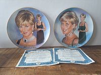 Two Lady Diana commemorative porcelain plates displayed with accompanying certificates of authenticity on wooden surface. Plates show portraits of Lady Diana with elegant backgrounds and gold rim accents.
