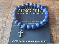 Front view of lapis lazuli bead bracelet with attached ankh charm on branded card