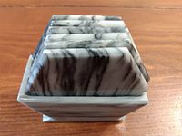 Stacked hexagonal onyx coasters inside a matching onyx base holder showing natural marbled stone pattern in grayscale.