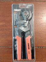 Full view of Finder punch plier in original packaging showing orange and black handles and punch mechanism.