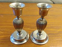 Pair of silver plated candle holders showing shape and finish on wood surface.