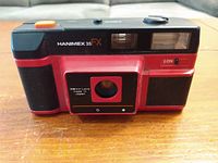 Front view of the Hanimex 35 FX camera showing red and black plastic body with lens and flash visible.