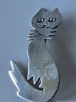 Front view of vintage sterling silver cat brooch showing stylized cat design and wear marks