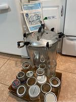 Pressure canner, jars, and instruction booklet arranged on floor