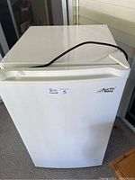 Front view of white Arctic King mini freezer with handle and brand logo visible, showing compact upright style and small footprint.