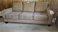 Front view of three-seat faux suede sofa with removable cushions and arms, tan color.