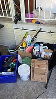 Photo showing lot includes garden hand tools, buckets, bins, bottles of chemicals, and miscellaneous gardening items on a patio.