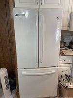 Front view of white GE refrigerator with double doors and bottom freezer drawer, showing exterior handle design.