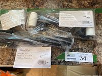 Three Pampered Chef kitchen tools in original plastic packaging: Bakers Roller, Mix 'N Chop, and Corn Cob Nobs, arranged on a countertop.