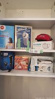 Shelved items including Life therapeutic hot bag, Clothes Shaver Plus, SureSafe face masks, and Philips shaver box