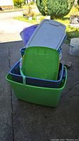 Plastic totes stacked together showing green, blue, purple, and gray lids and totes