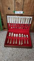 Full view of the silver plated cutlery set with 9 place settings in a lined red case shown open.