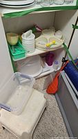 Photo of shelves containing assorted vintage Tupperware and plastic kitchen items including trays, containers, pitchers, and utensils.