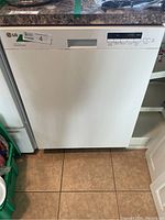 Front view of white LG dishwasher installed under counter with standard sized door.